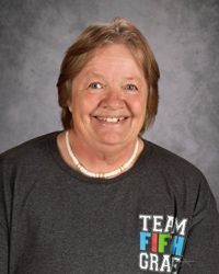Smiling person in a dark gray TEAM FIGHT GRAPHIC T-shirt against a gray backdrop