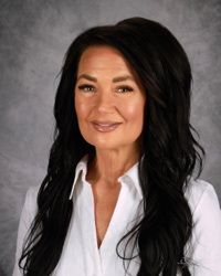 Portrait of a smiling woman in a white blouse with long dark hair on a gray background