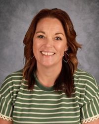 Smiling woman in green striped shirt against a gray studio backdrop