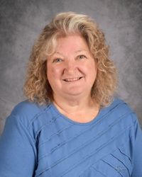 Smiling woman in a blue top against a gray studio backdrop