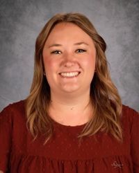 Smiling woman in a maroon top against a gray studio backdrop