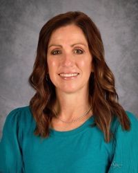 Portrait of a smiling person in a teal top against a gray studio background
