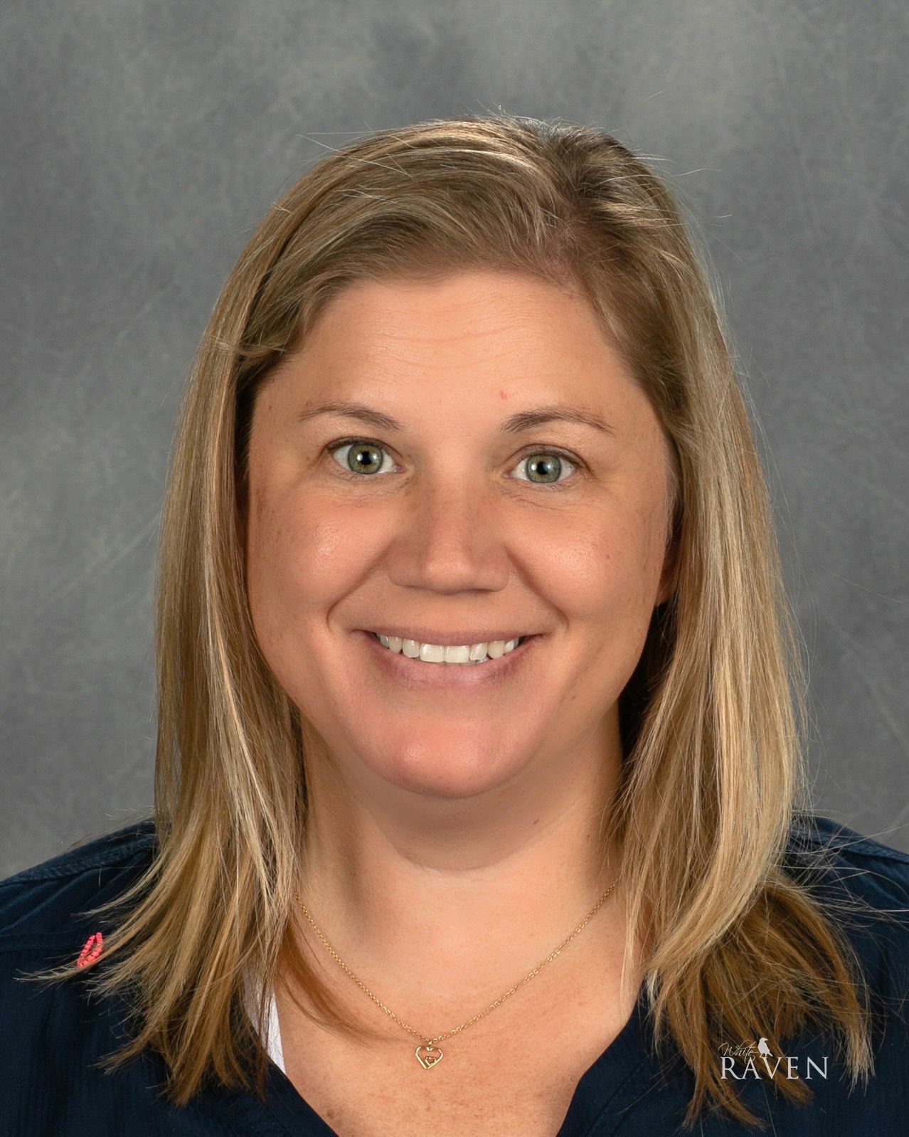 Portrait of a smiling woman with shoulder-length blonde hair against a gray background