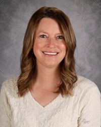 Smiling woman in a cream sweater against a gray studio backdrop