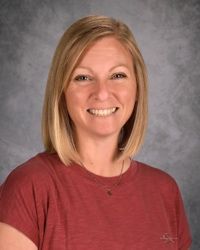 Smiling person in a red shirt against a gray studio backdrop