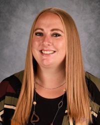 Smiling woman with long straight blonde hair against a gray studio backdrop
