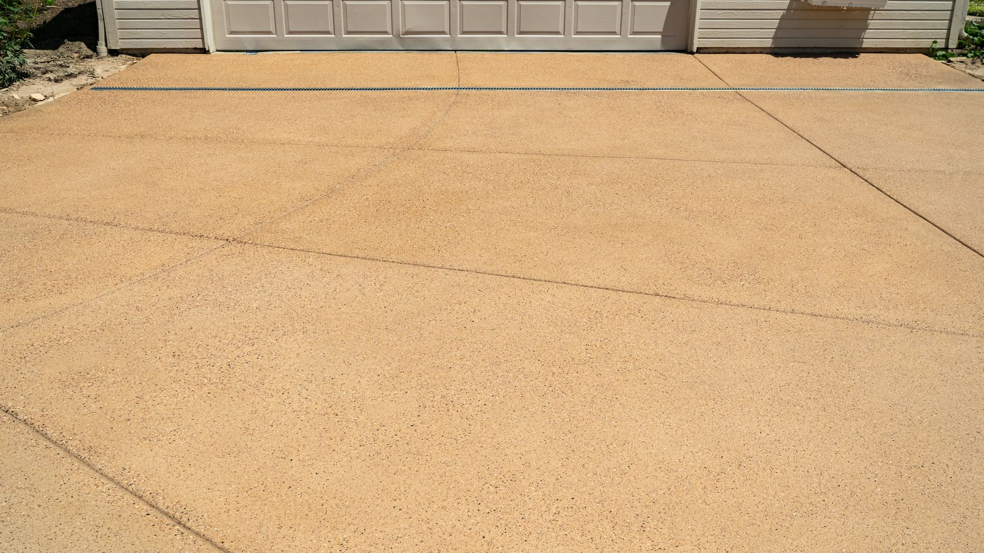 Sunlit concrete driveway in front of a garage door