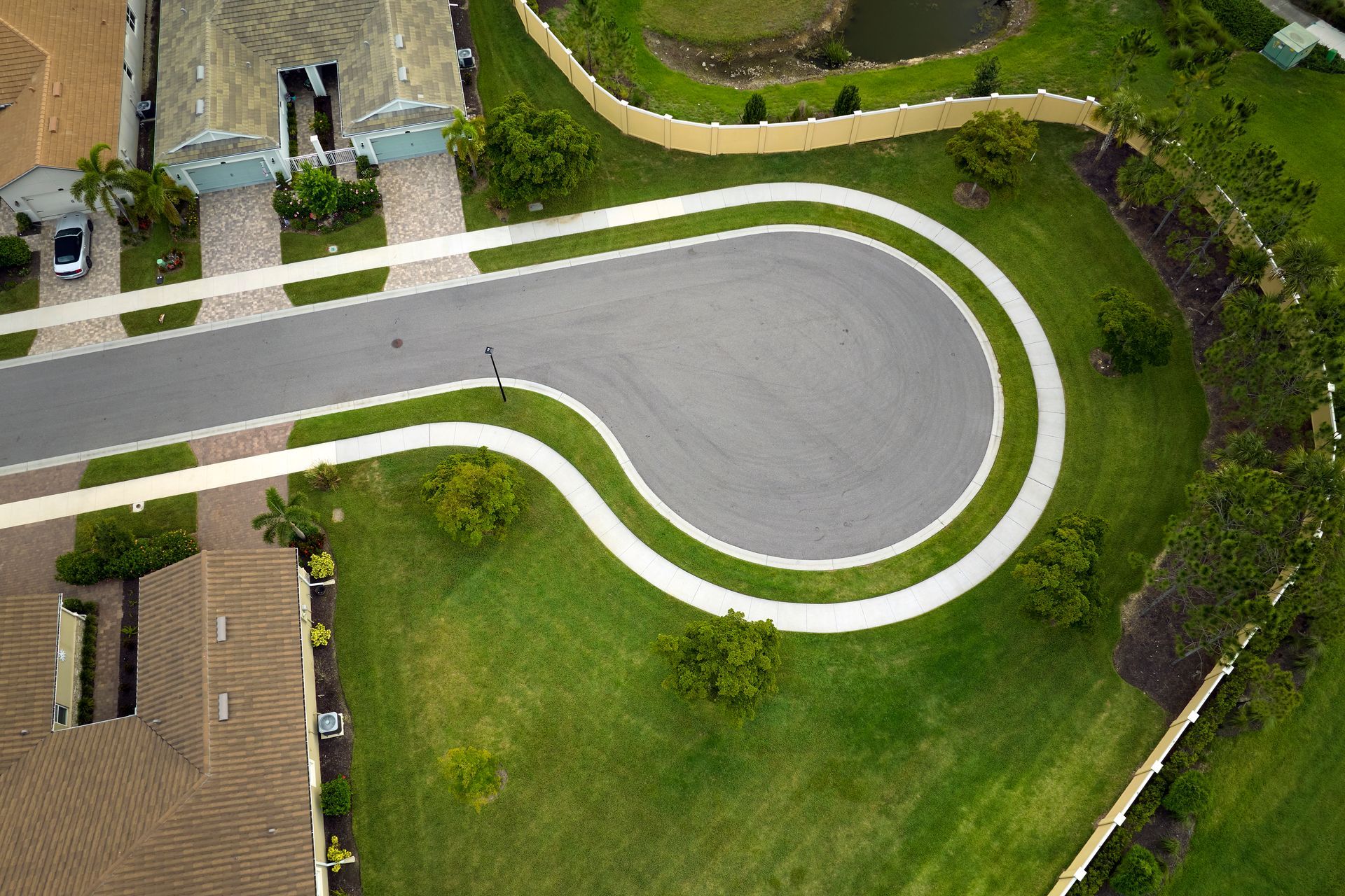 Aerial view of a curving driveway beside a green lawn and buildings