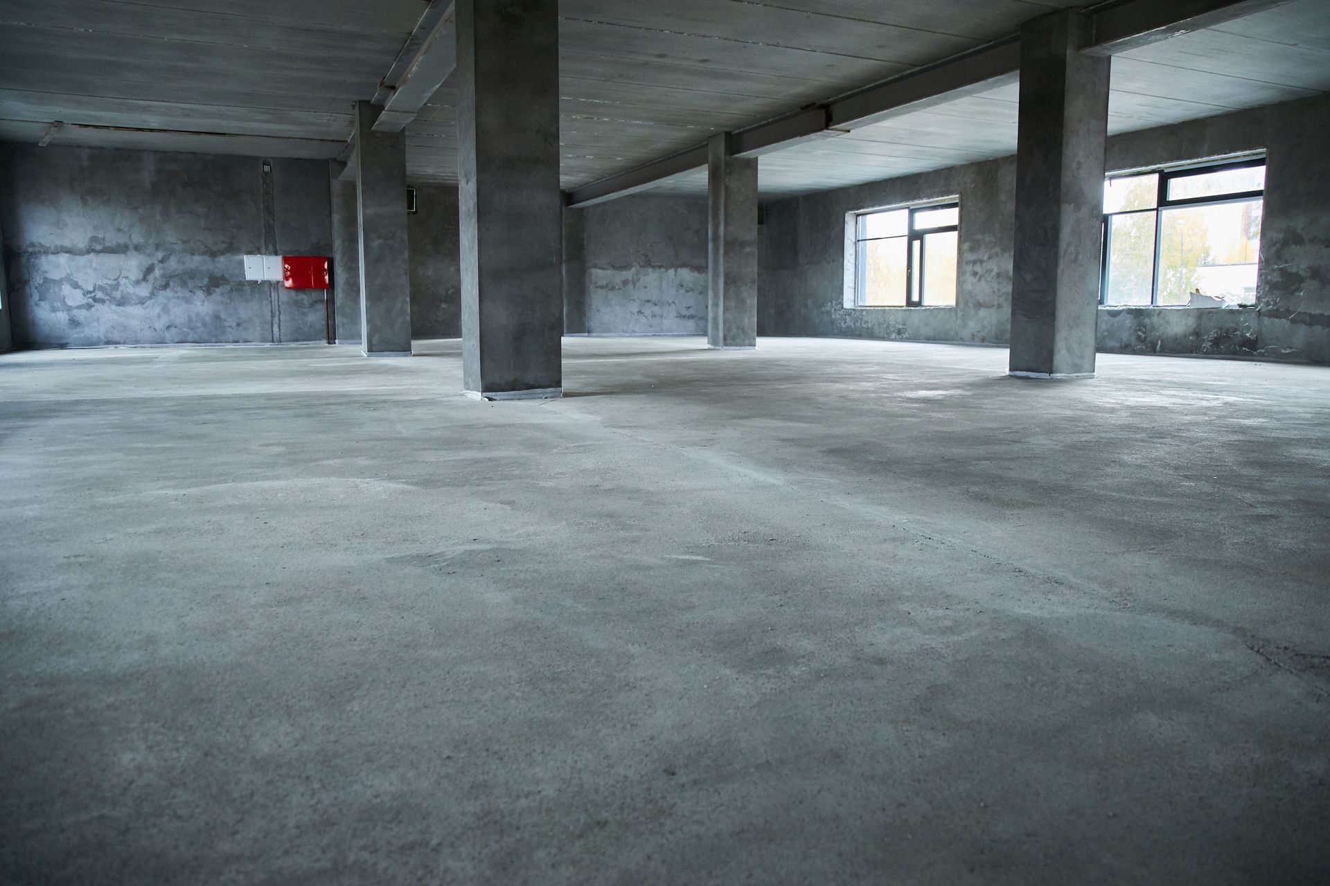 Empty concrete warehouse interior with pillars and windows