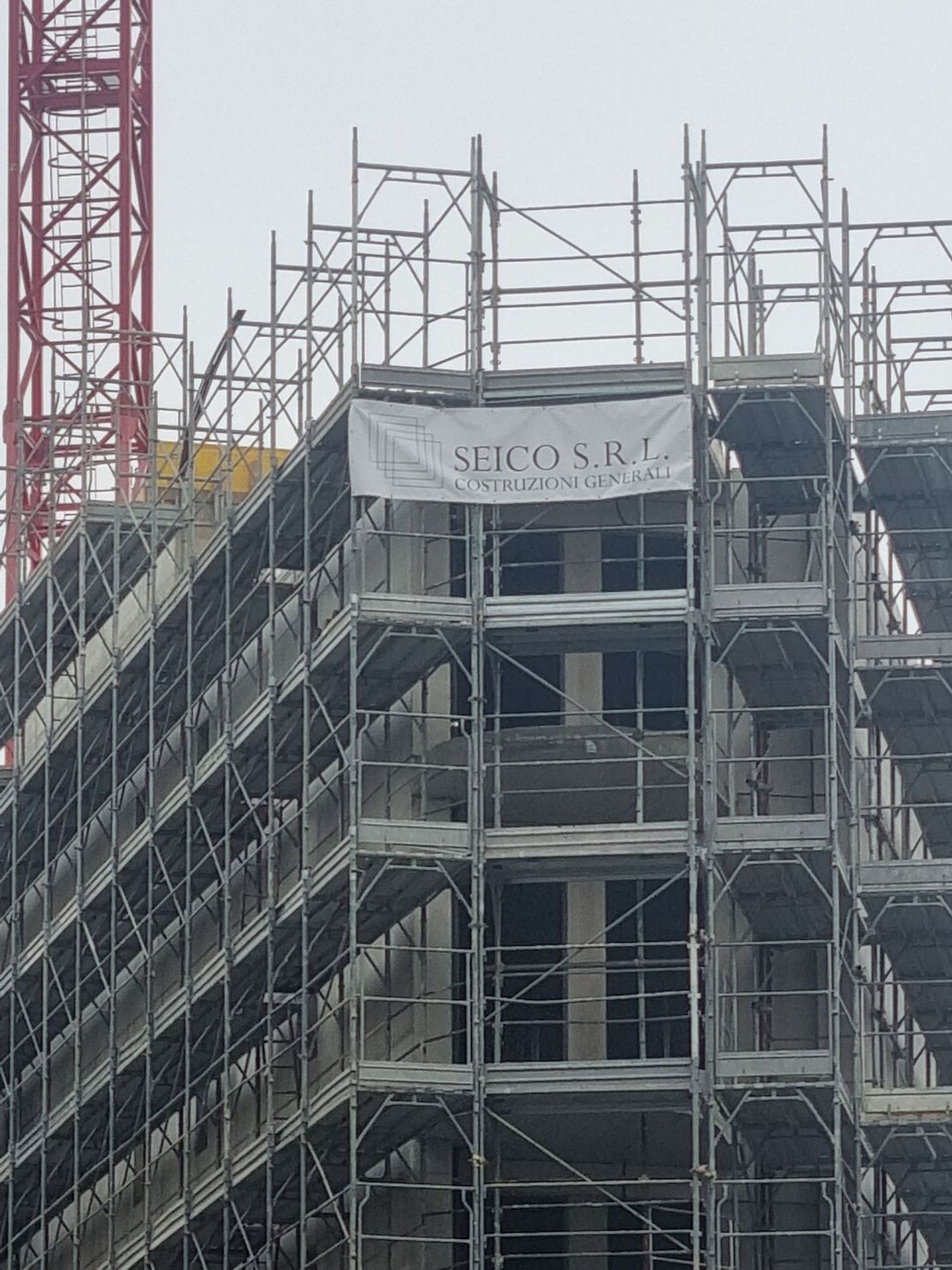 Casa in ristrutturazione, impalcature, muri gialli, furgone bianco parcheggiato davanti, neve per terra.