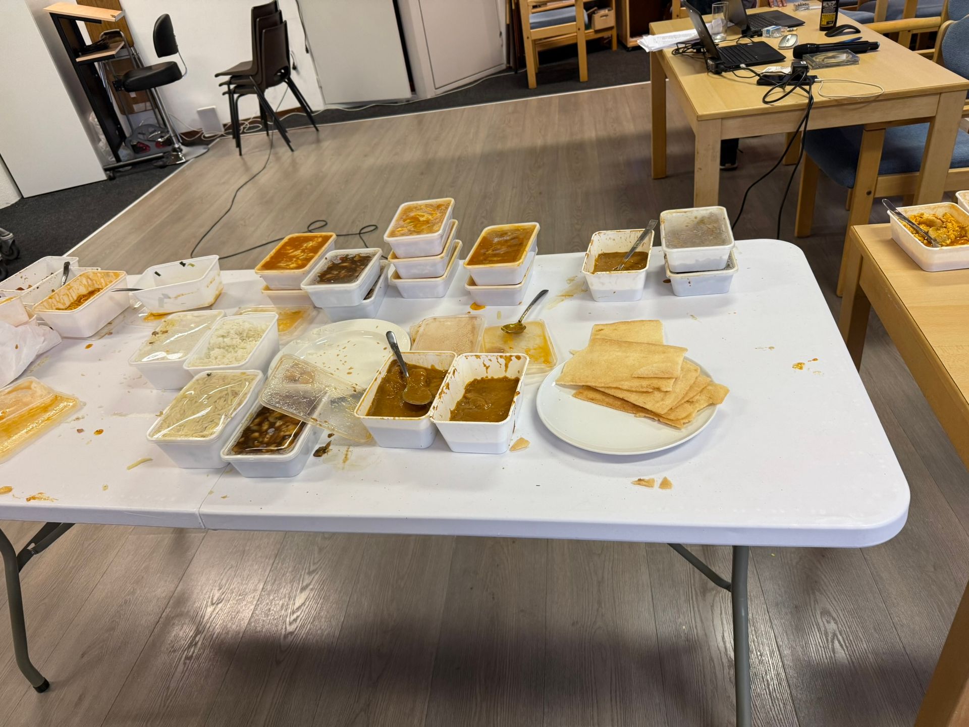 Tafel vol Indiaas eten in bakjes: rijst, curry's en crackers. Kamersetting.