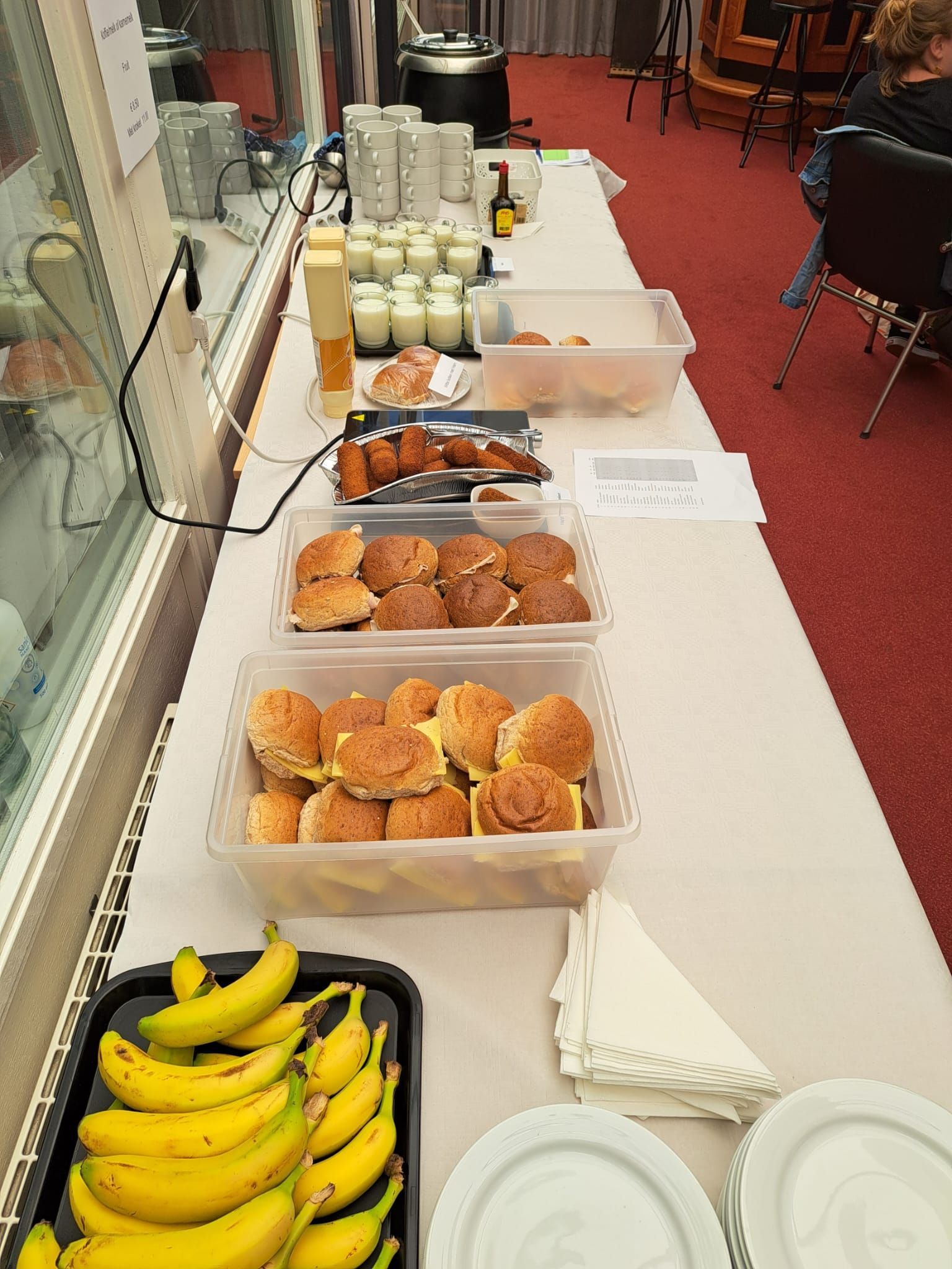 Een buffettafel vol met eten: bananen, broodjes, gebak, yoghurt en eieren.