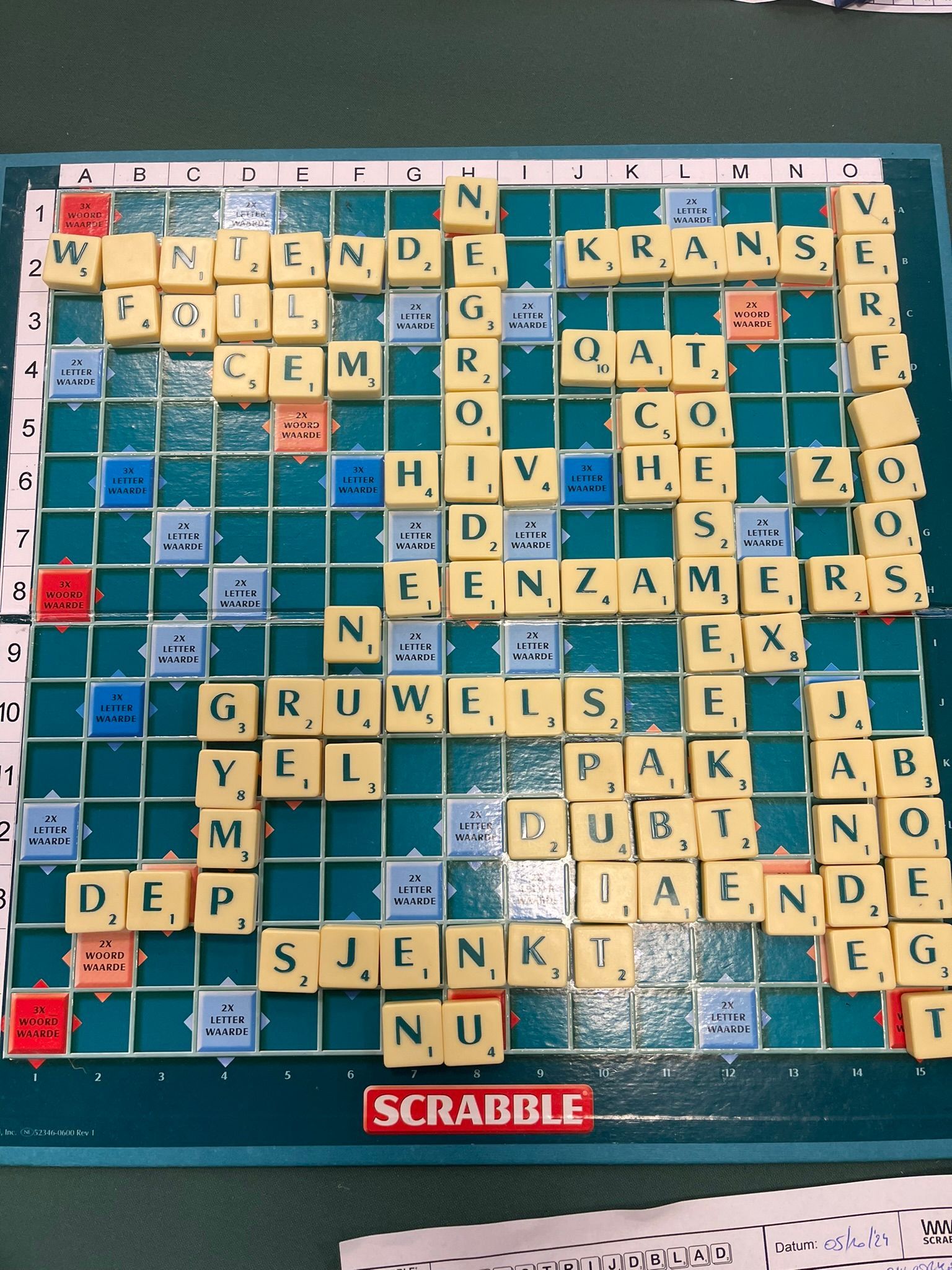 Scrabblebord met beige lettertegels, waarop verschillende woorden zijn gevormd. Het bord is groen met een Scrabble-logo.
