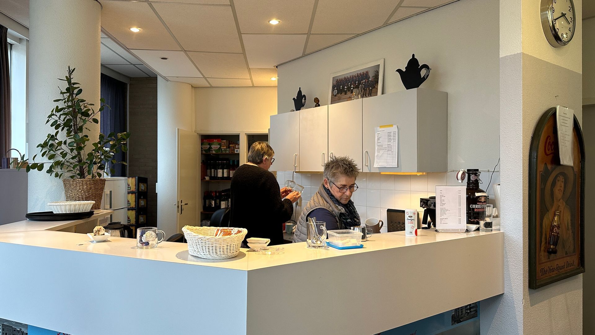 Twee mensen staan ​​aan de toonbank in een klein café. Eén van hen staat achter de toonbank en bereidt drankjes.
