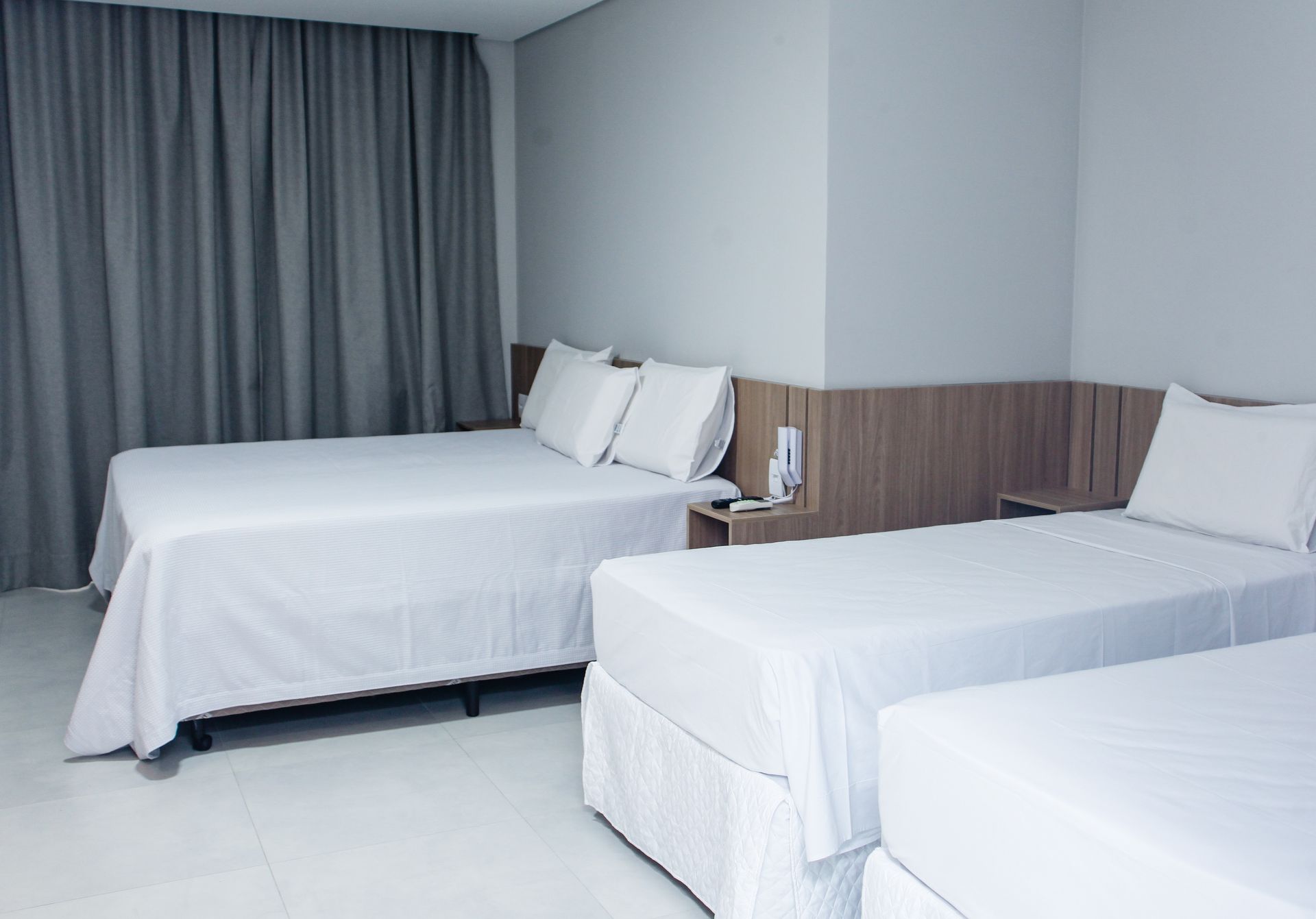Um quarto de hotel com três camas e um telefone. Hotel Solar Paulista