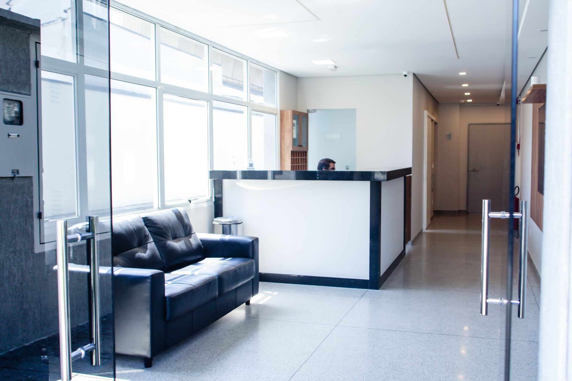 Uma sala de espera com um sofá e uma porta de vidro Hotel Solar Paulista