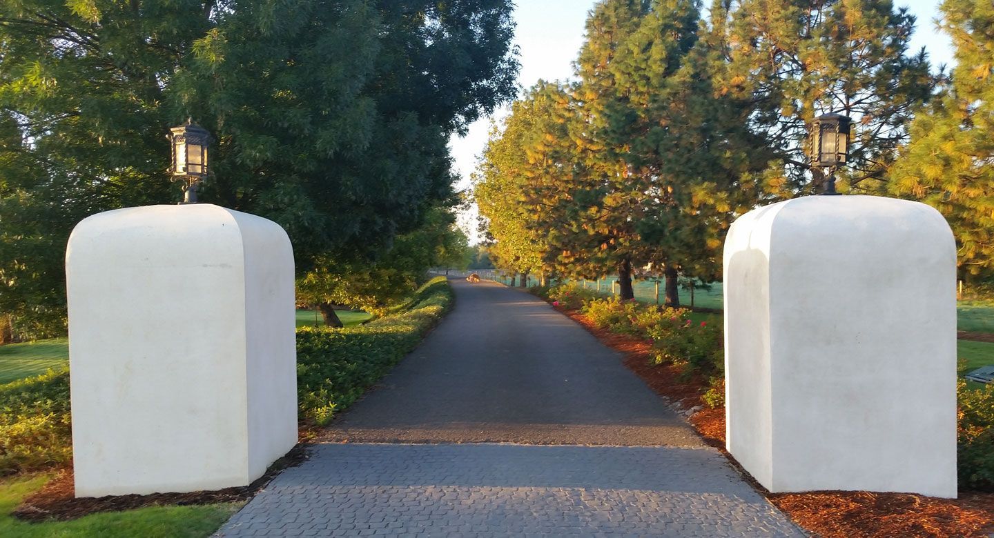 A driveway with two white pillars on the side of it