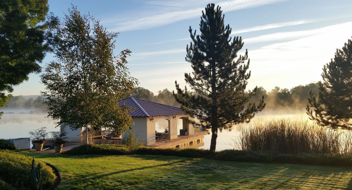 A house is sitting on the shore of a lake surrounded by trees.