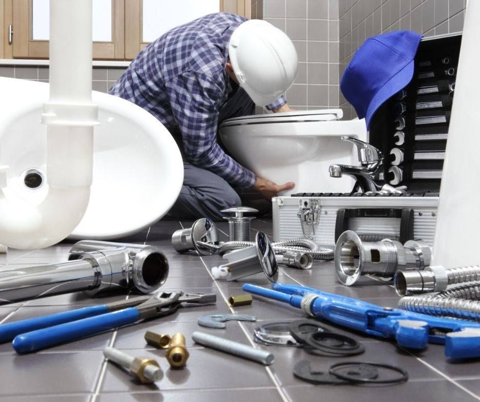 A Plumber is Working on a Toilet in a Bathroom — Wigg Plumbing in Berry Springs, NT