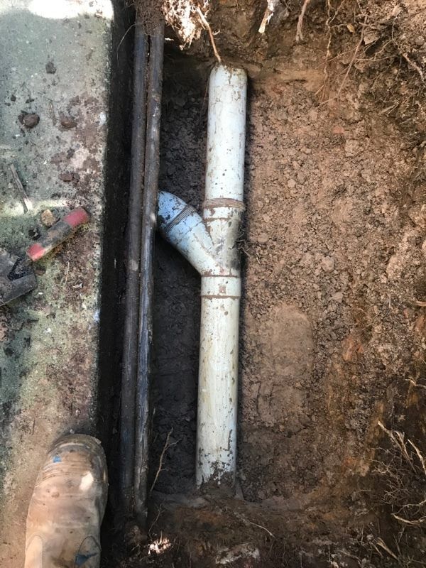 A White Pipe is Sitting in the Dirt Next to a Metal Pipe — Wigg Plumbing in Berrimah, NT