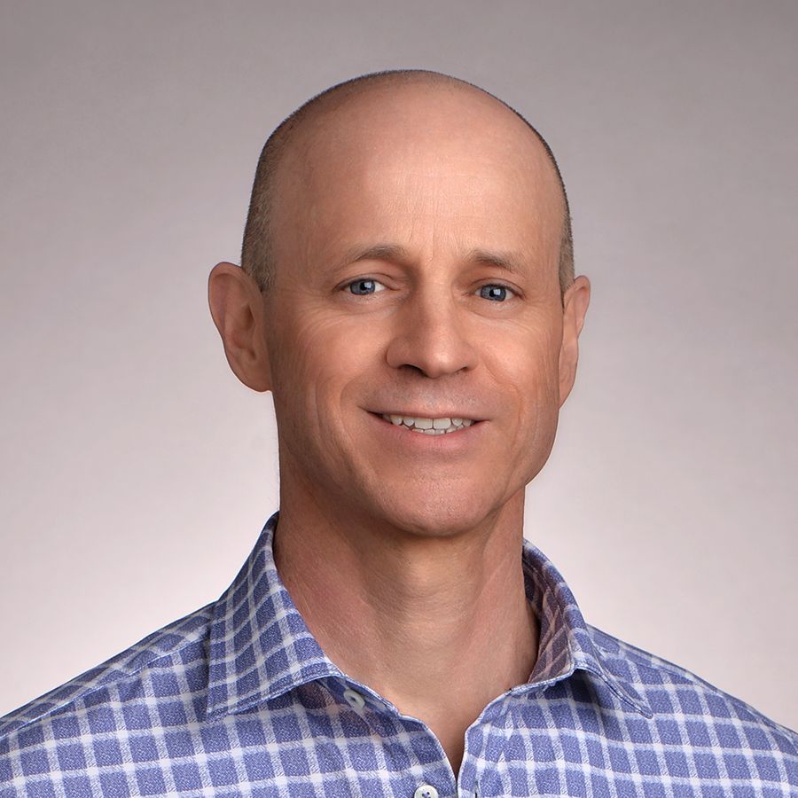 A person wearing a blue and white checkered shirt is smiling for the camera.