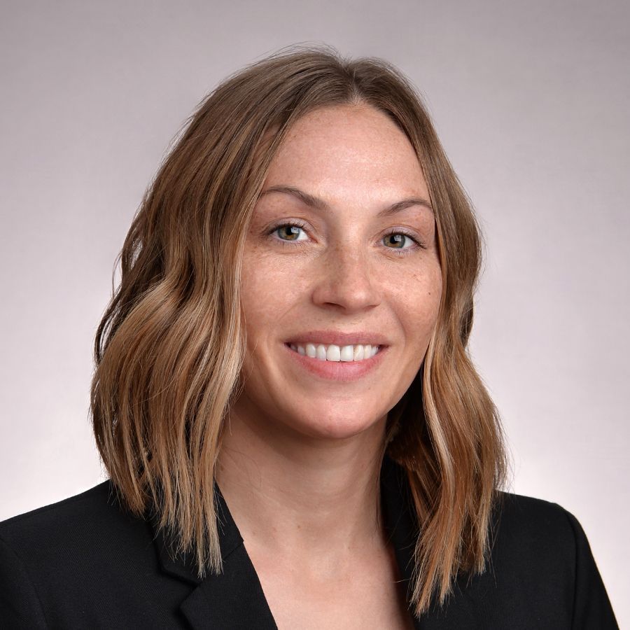 A person in a black jacket is smiling for the camera.
