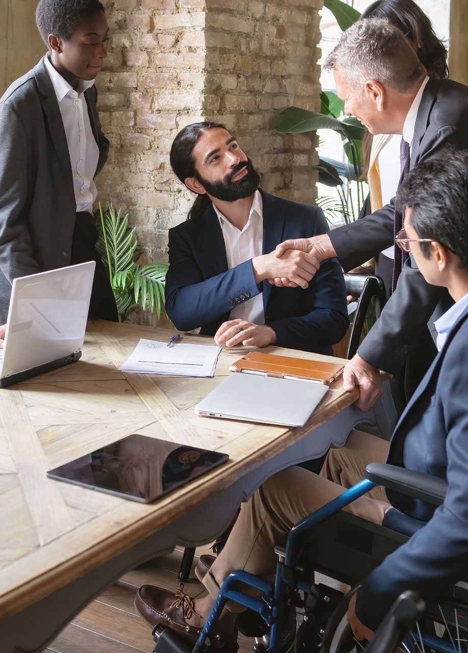 A man in a wheelchair is shaking hands with a man in a suit.
