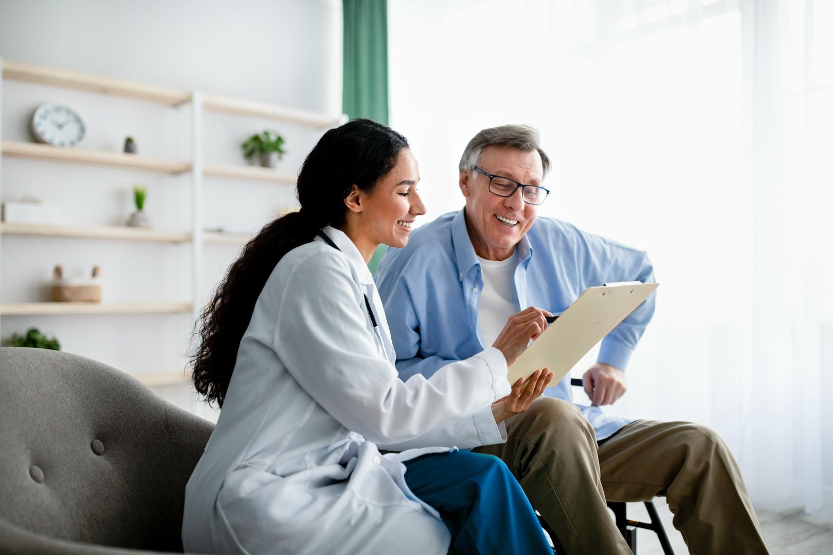 Doctor showing paperwork to smiling senior man in a bright room.