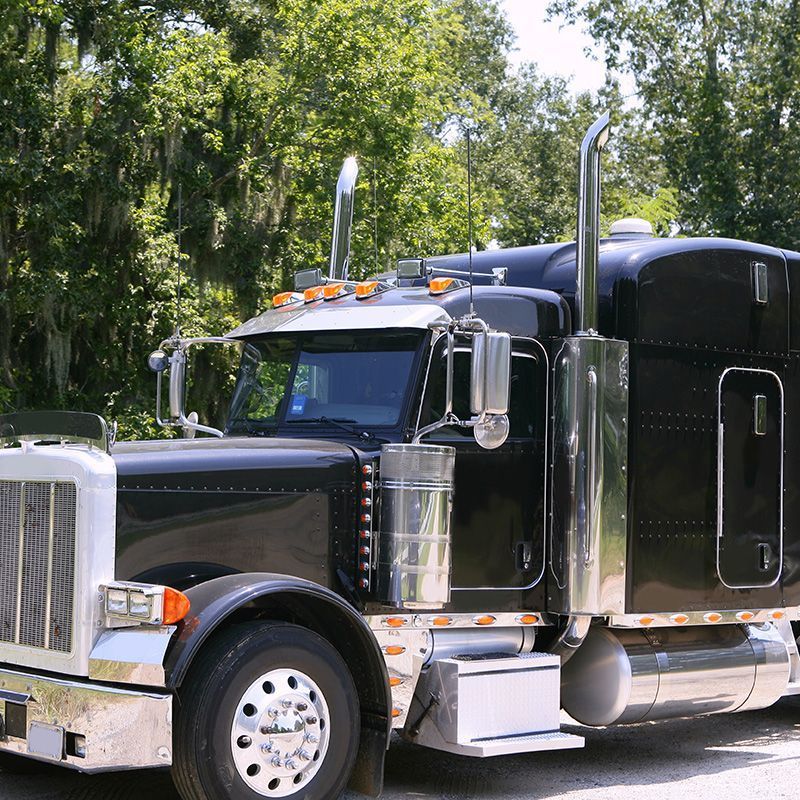 A black semi truck is parked on the side of the road