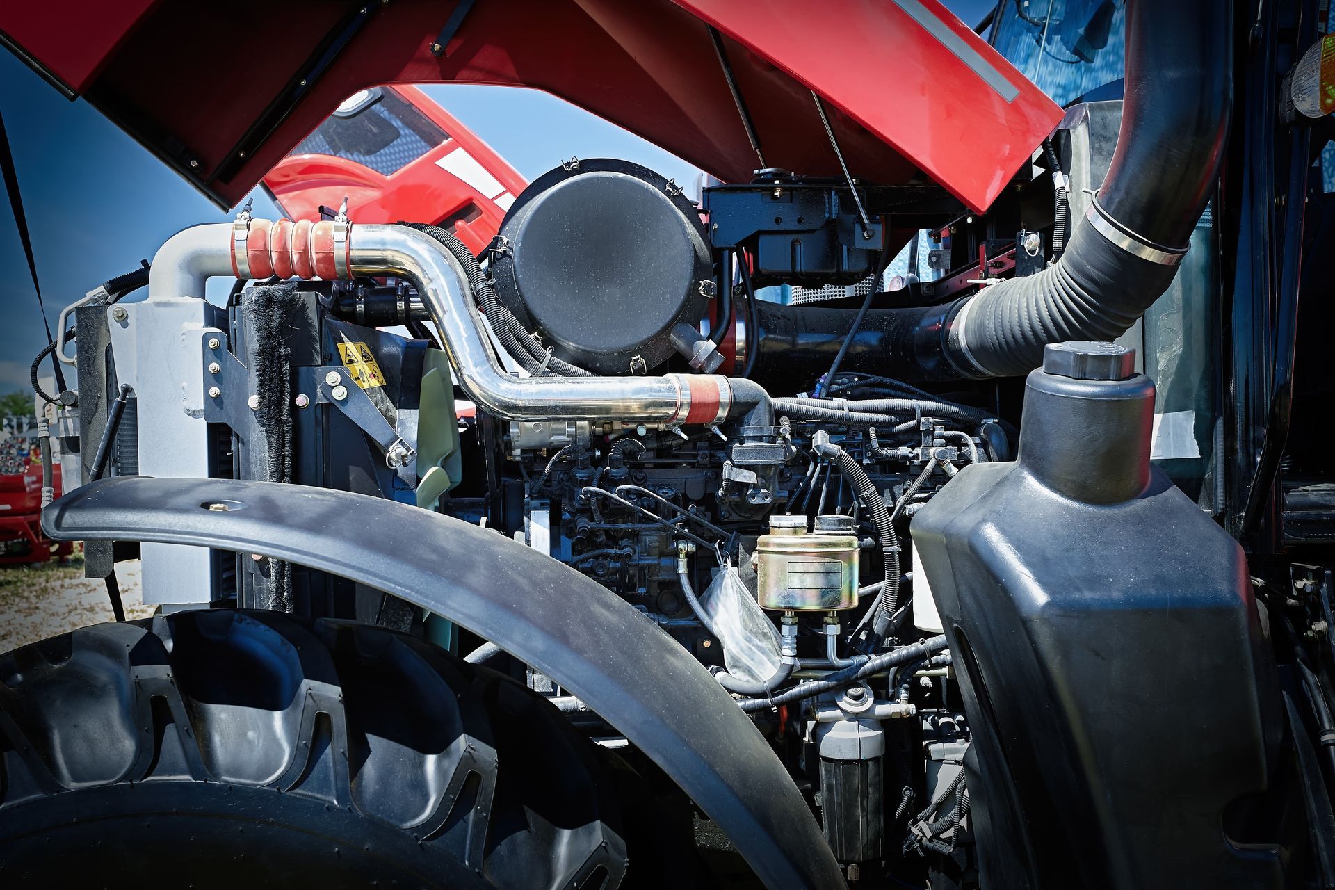 Engine of a red tractor with the hood open, revealing its components.