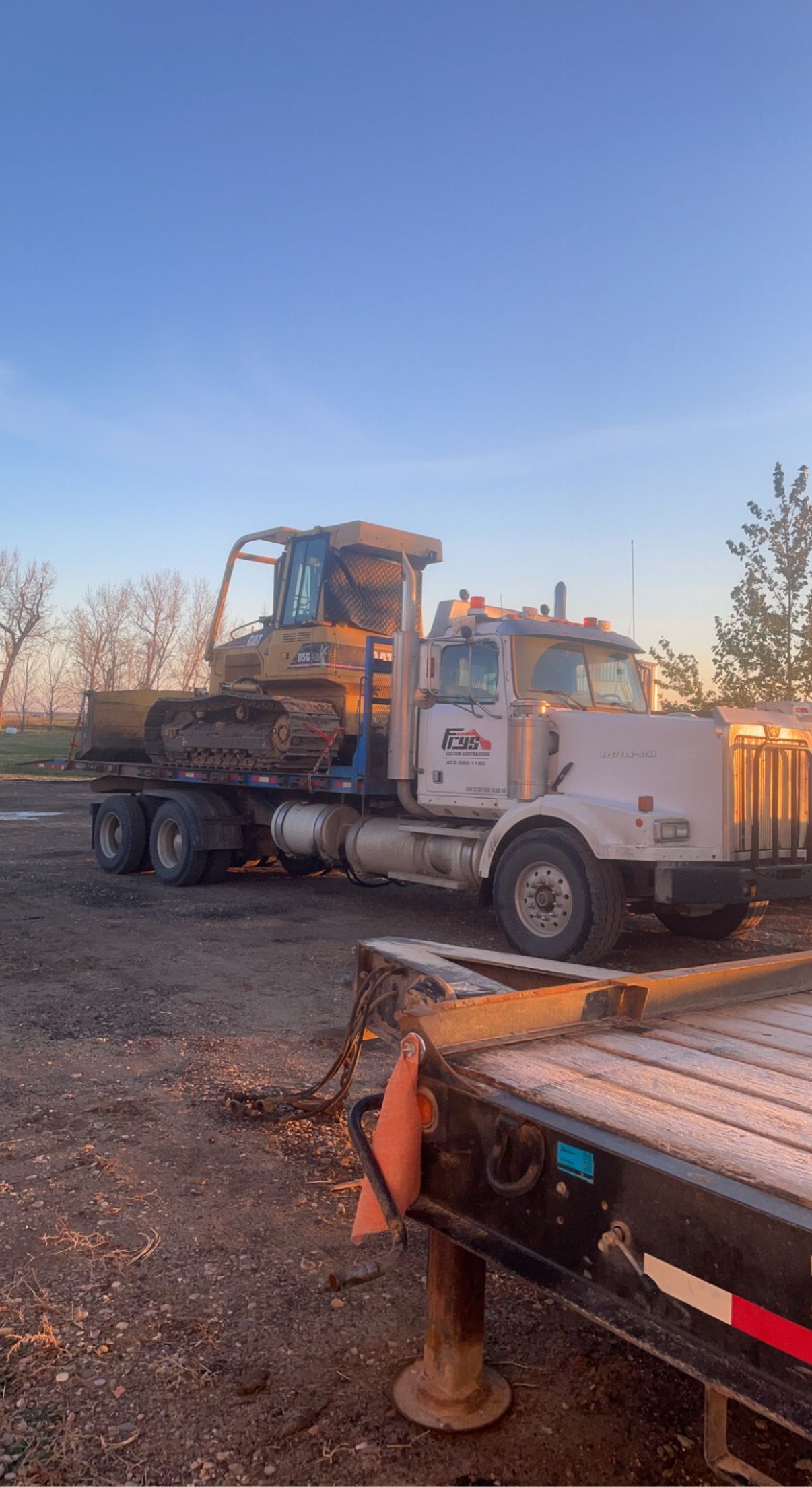 A truck is towing a bulldozer on a trailer.