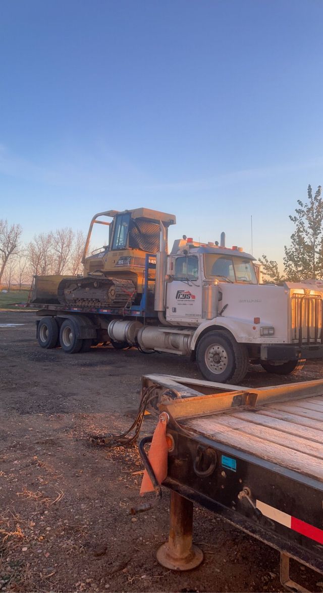 A truck is towing a bulldozer on a trailer.