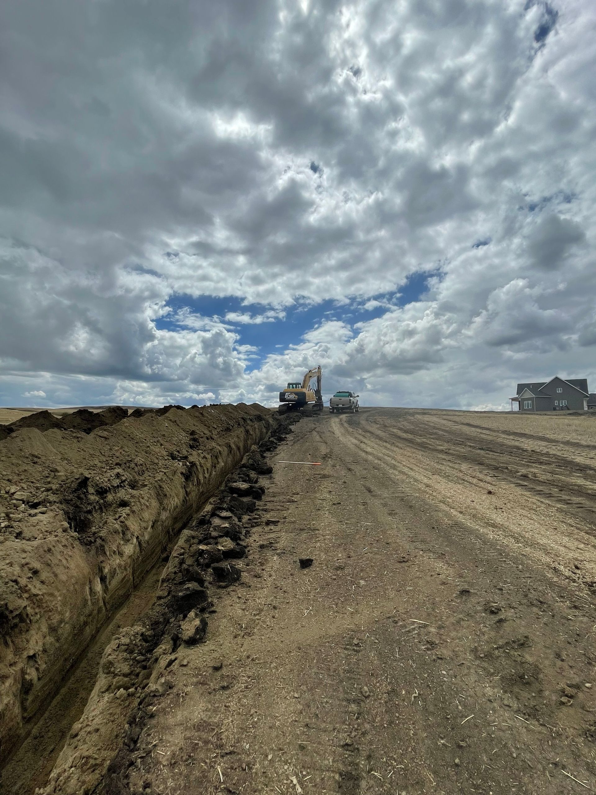 A truck is driving down a dirt road with a cloudy sky in the background.