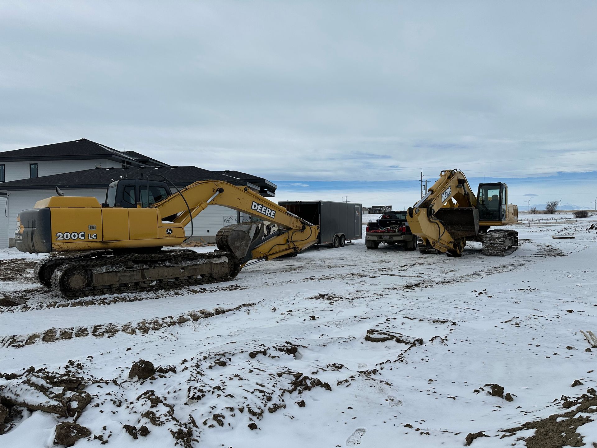 A couple of construction vehicles are parked in a snowy field.