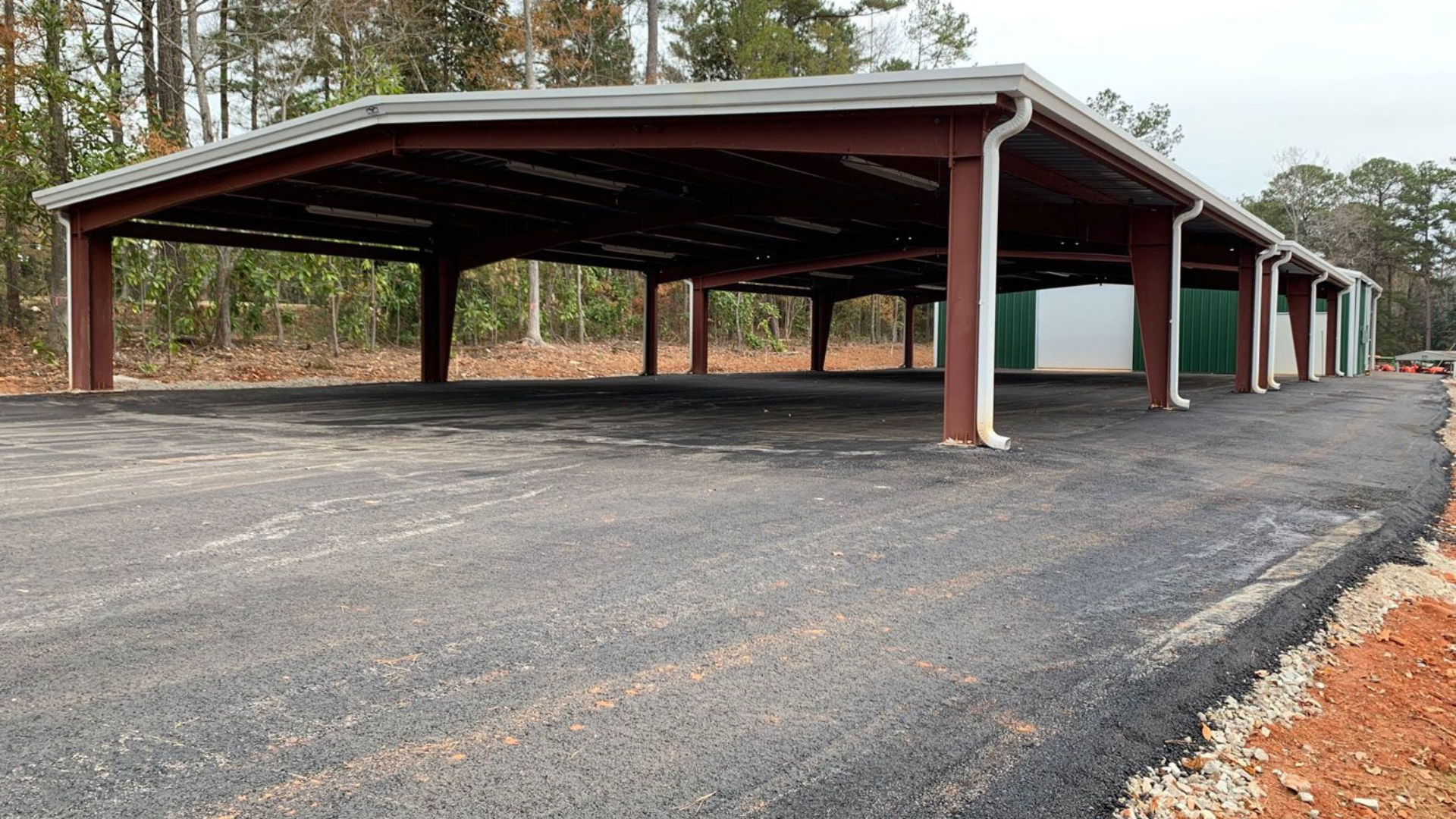 A row of parking spaces with a roof and gutters in a parking lot.