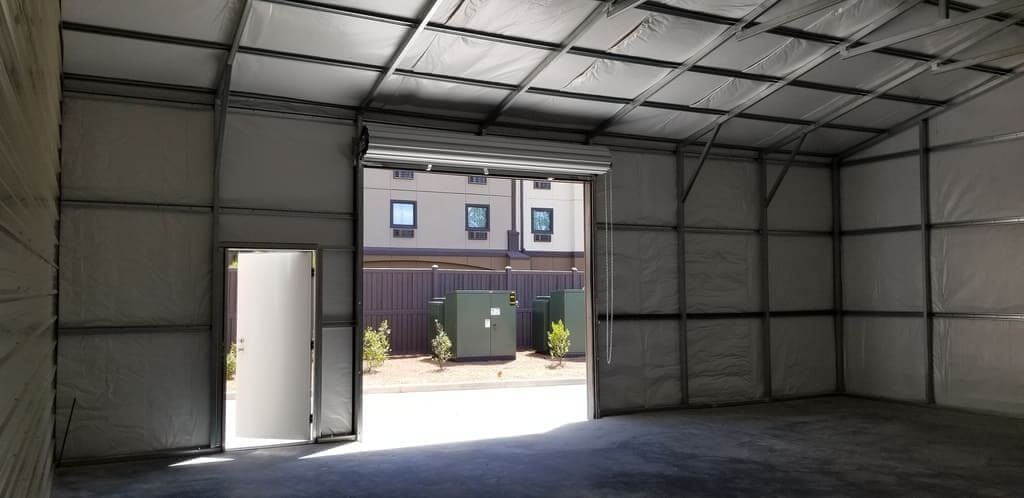 An empty garage with a door open and a building in the background.