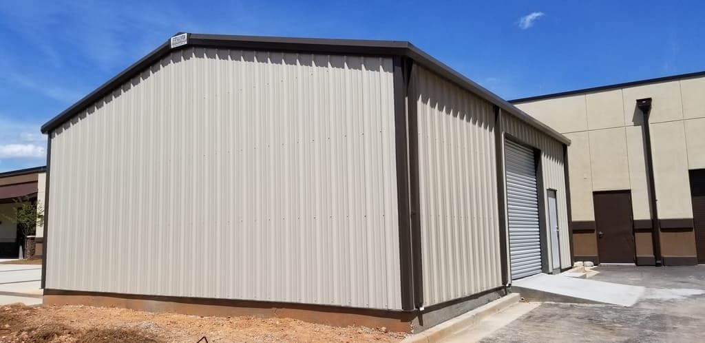 A large metal building is sitting in front of a building.