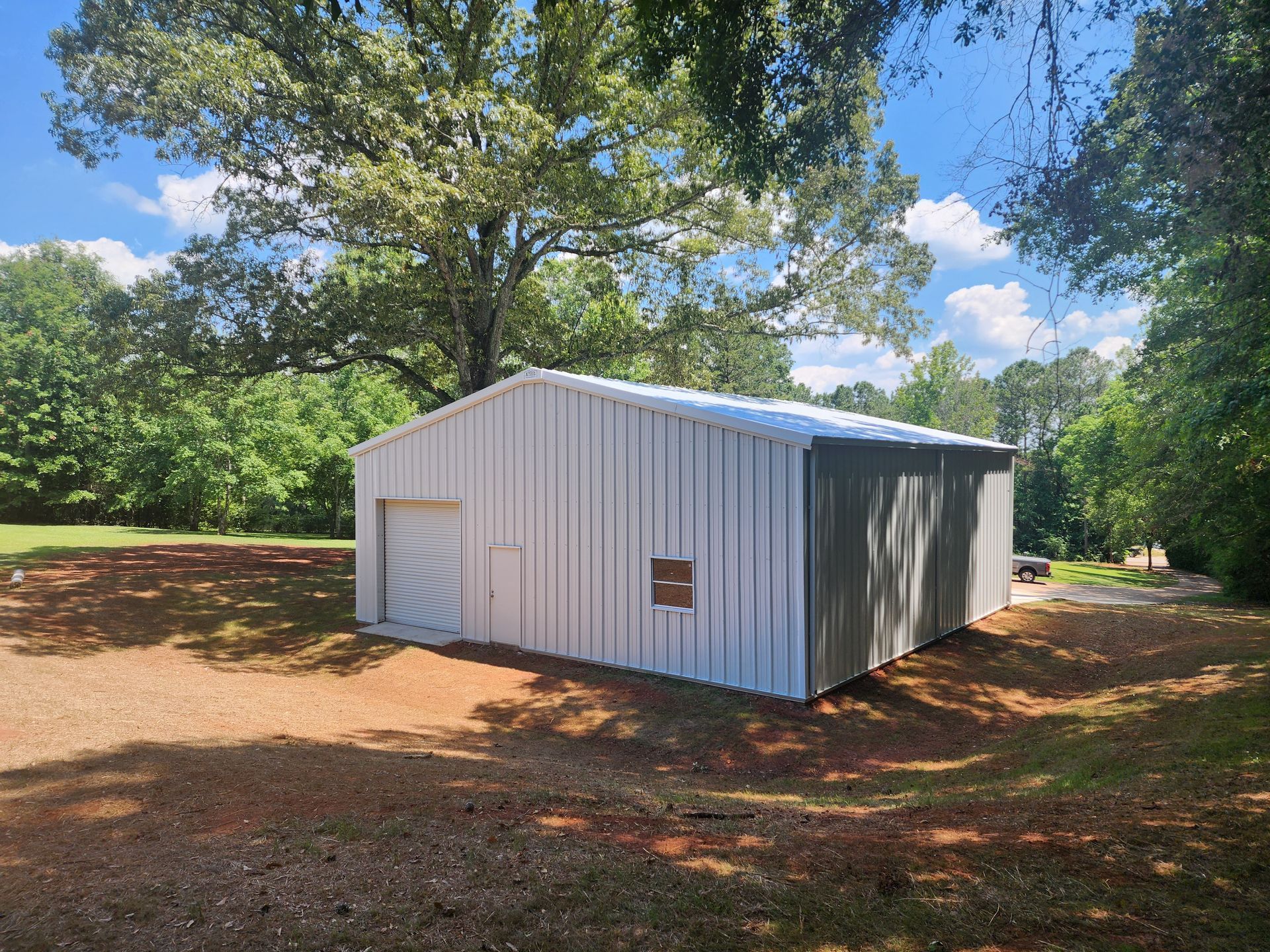 A large metal building is sitting in the middle of a field surrounded by trees.
