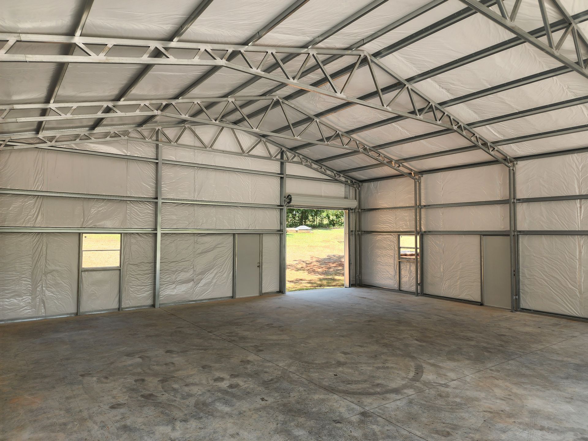 A large empty building with a concrete floor and a metal roof.