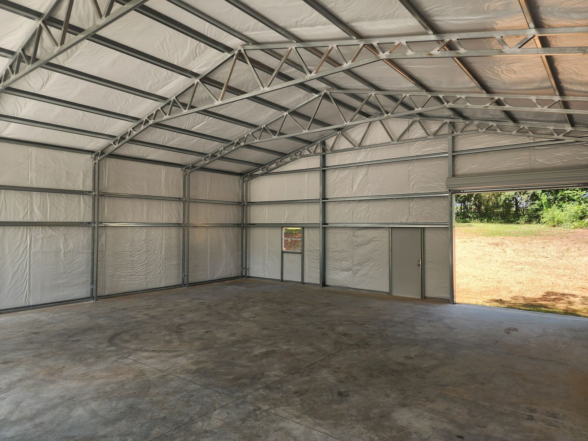 A large empty building with a roof and a concrete floor.