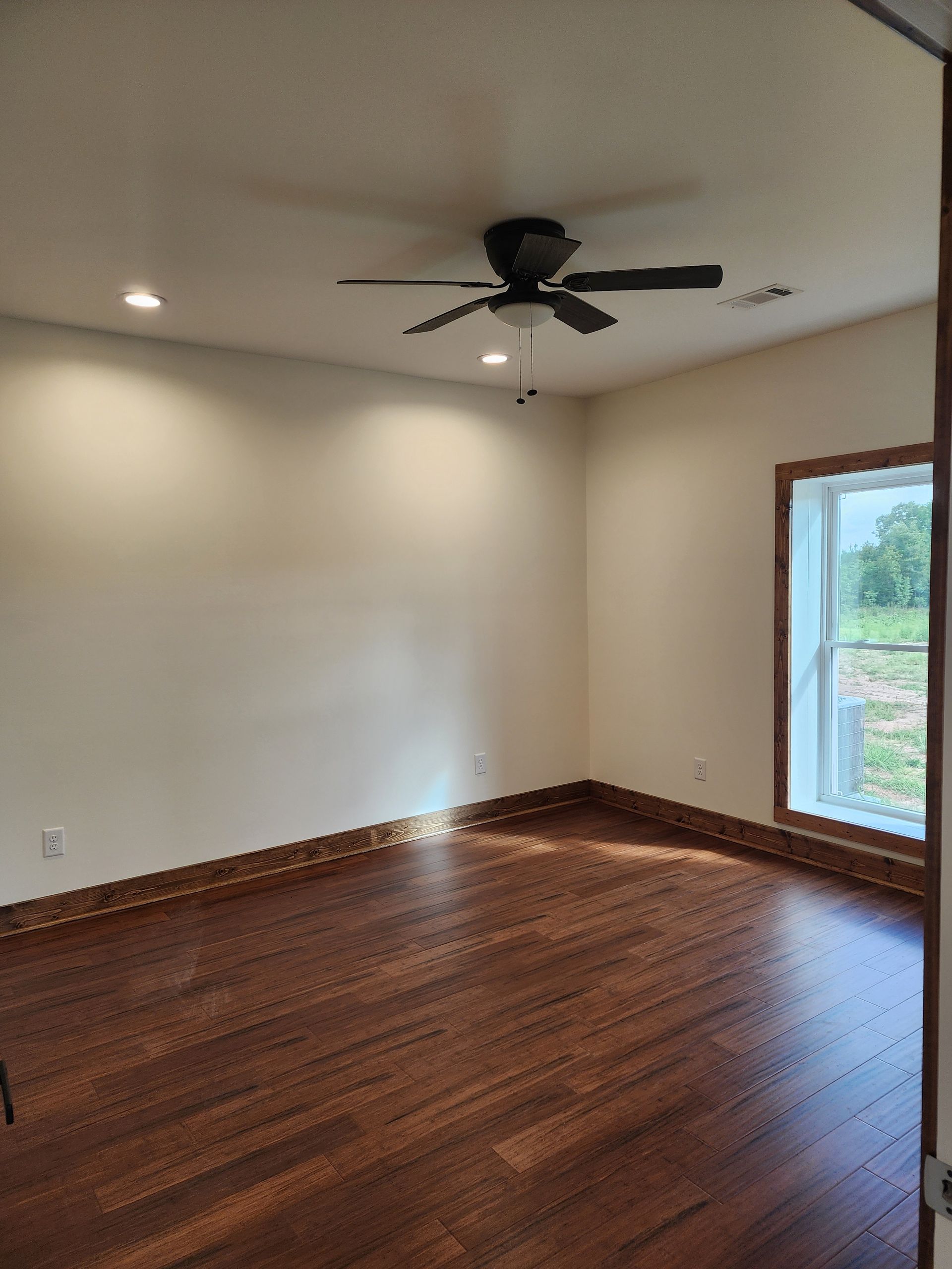 An empty room with hardwood floors and a ceiling fan.
