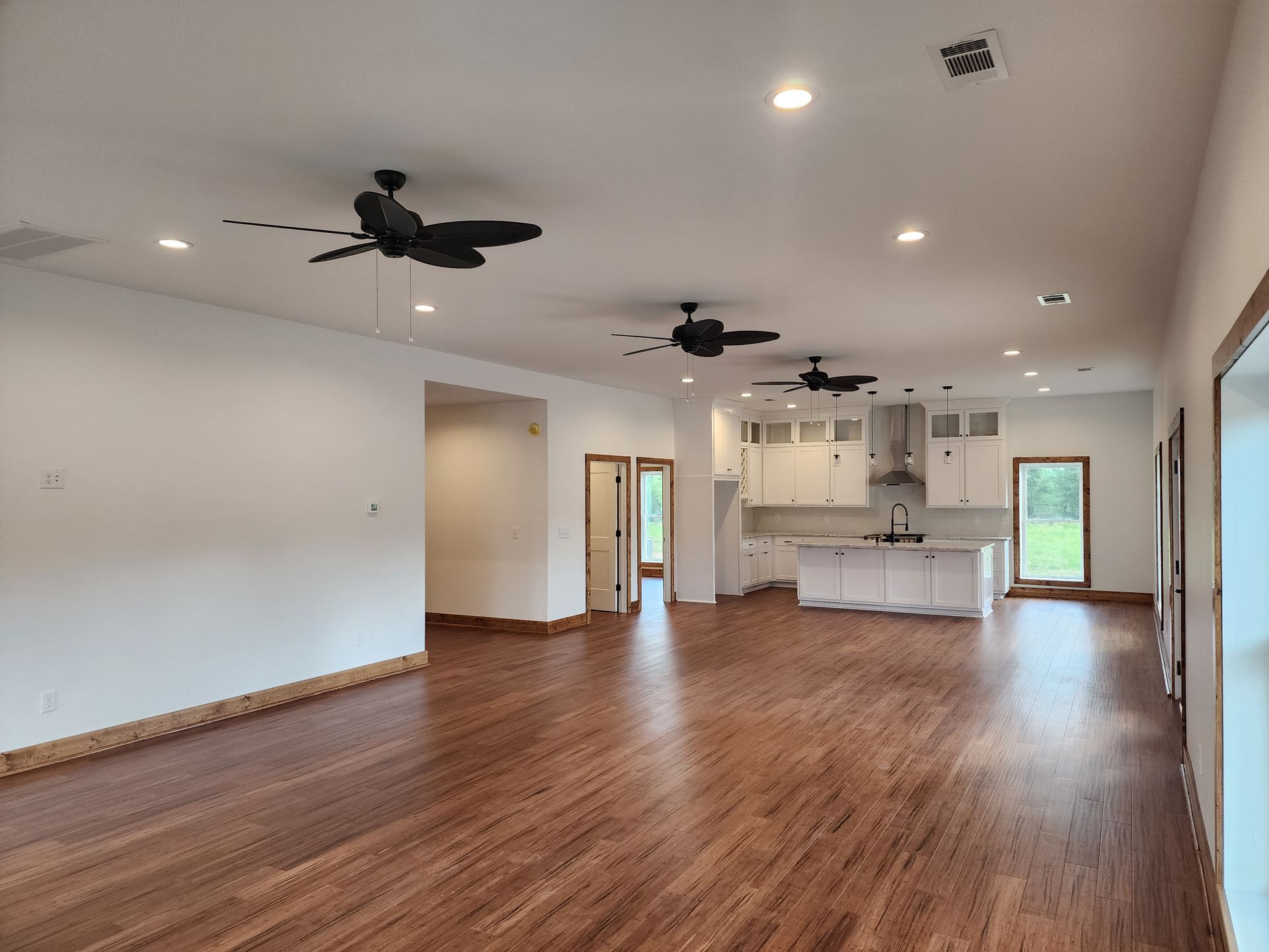 A large empty room with hardwood floors and ceiling fans.