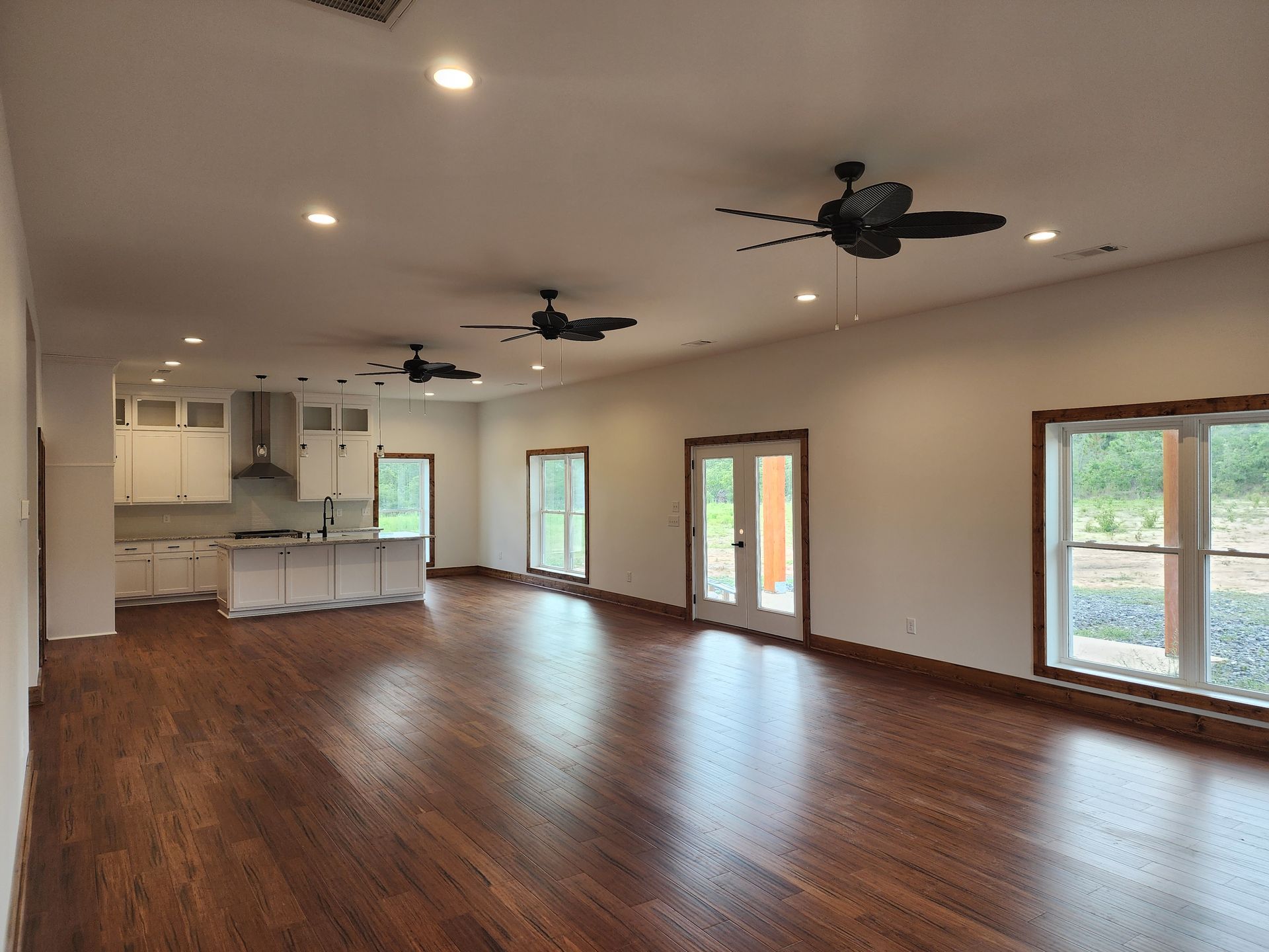 A large empty room with hardwood floors and ceiling fans.