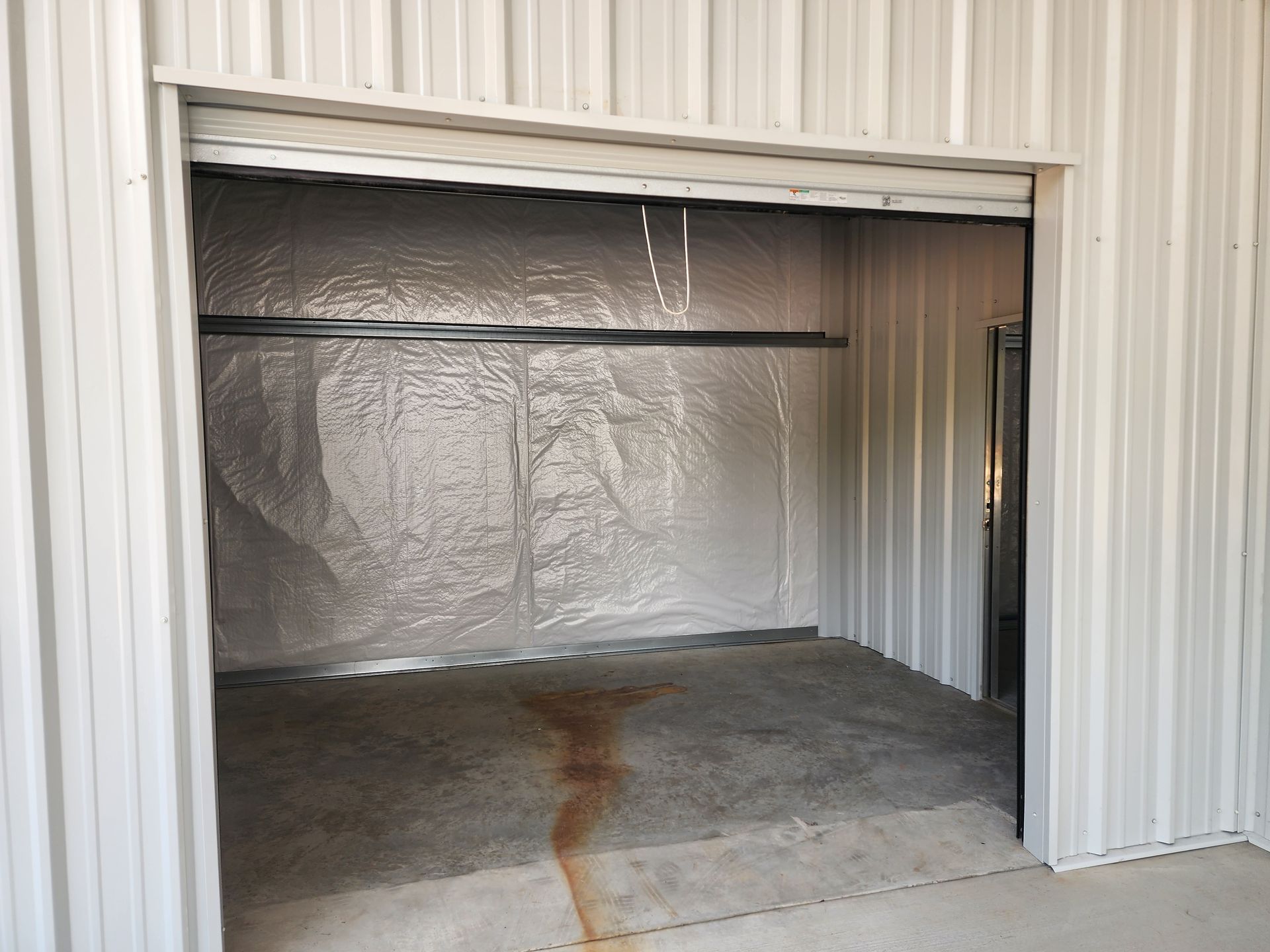 An empty storage unit with a sliding door and a concrete floor.
