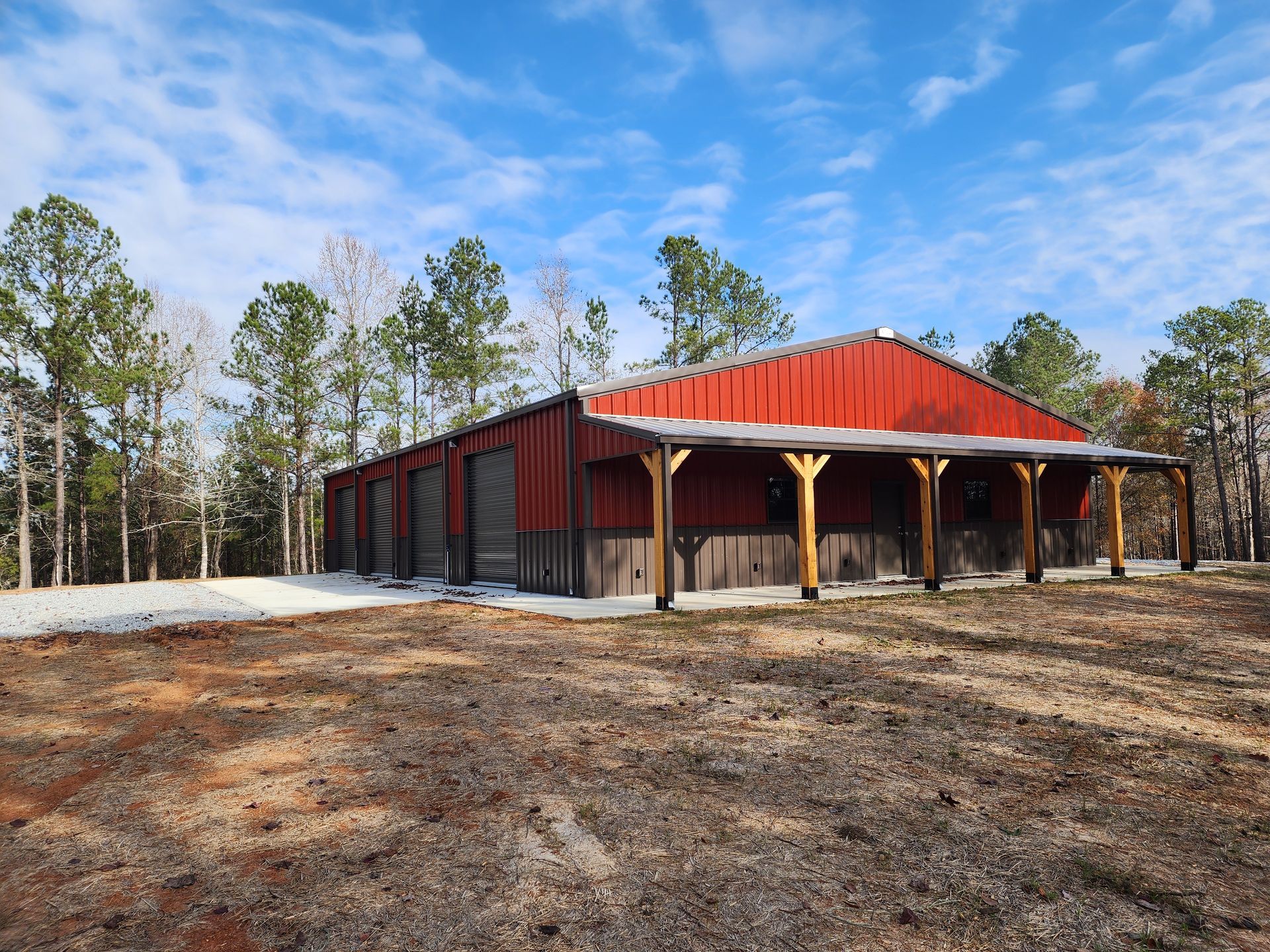Red-roofed pavilion with open sides in a cleared wooded area under a blue sky