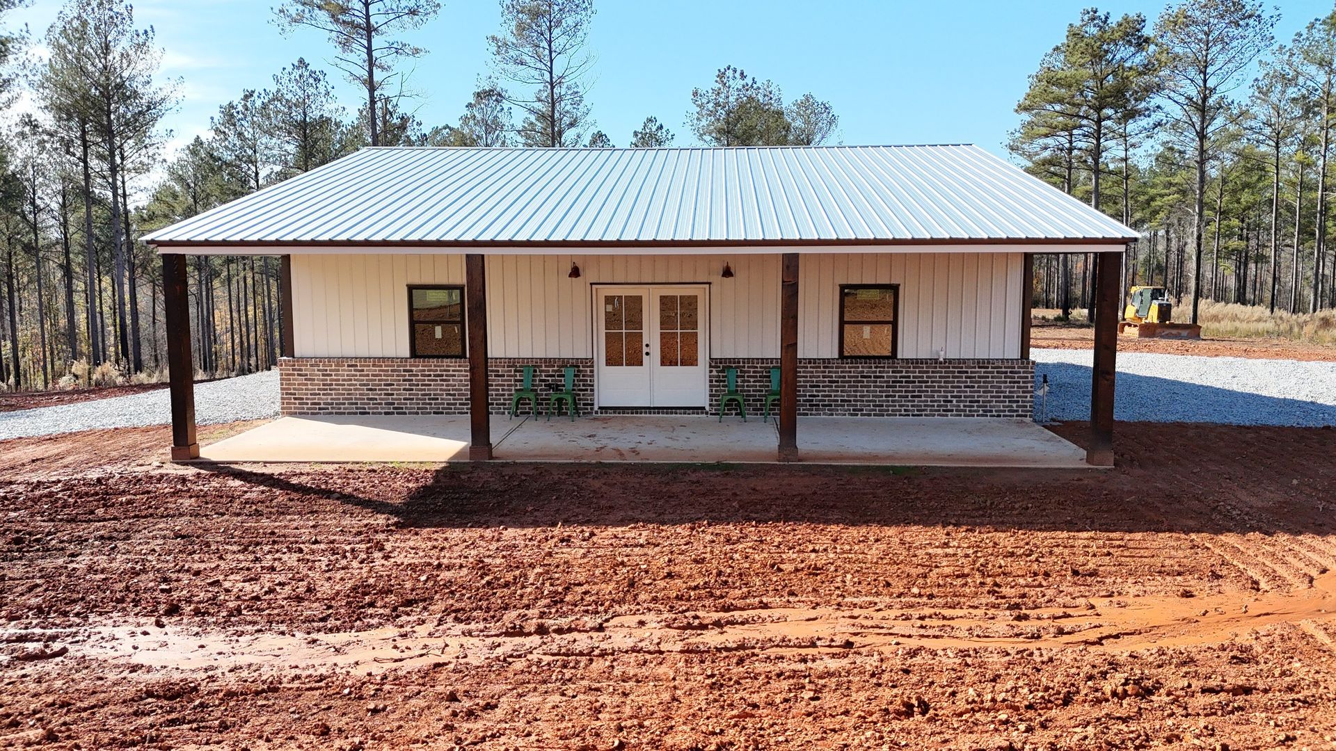 A white house with a porch in the middle of a dirt field