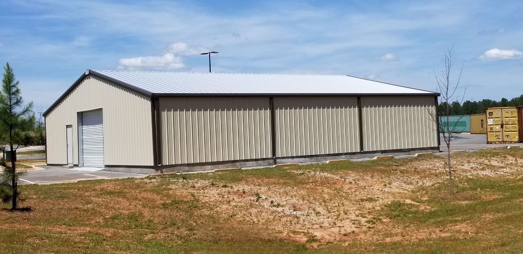 A large metal building is sitting in the middle of a grassy field.