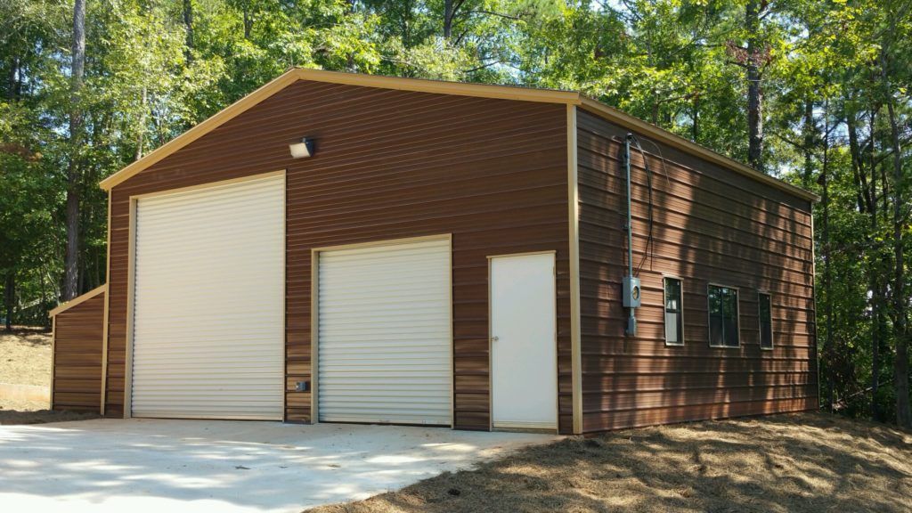 A brown garage with a white door is surrounded by trees