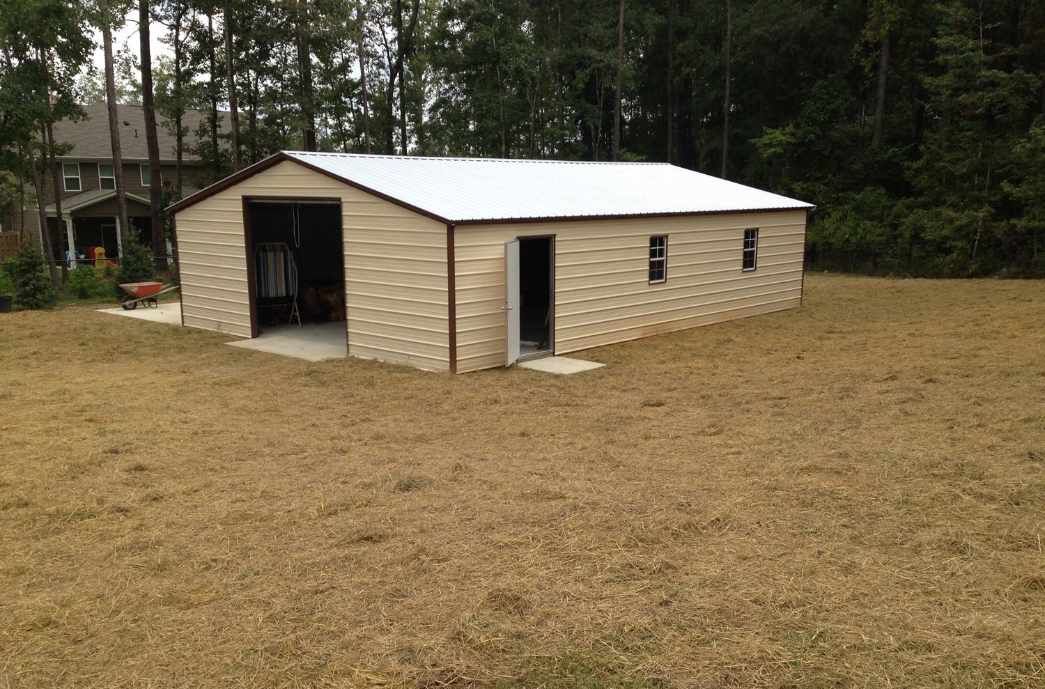 A metal garage is sitting in the middle of a grassy field.