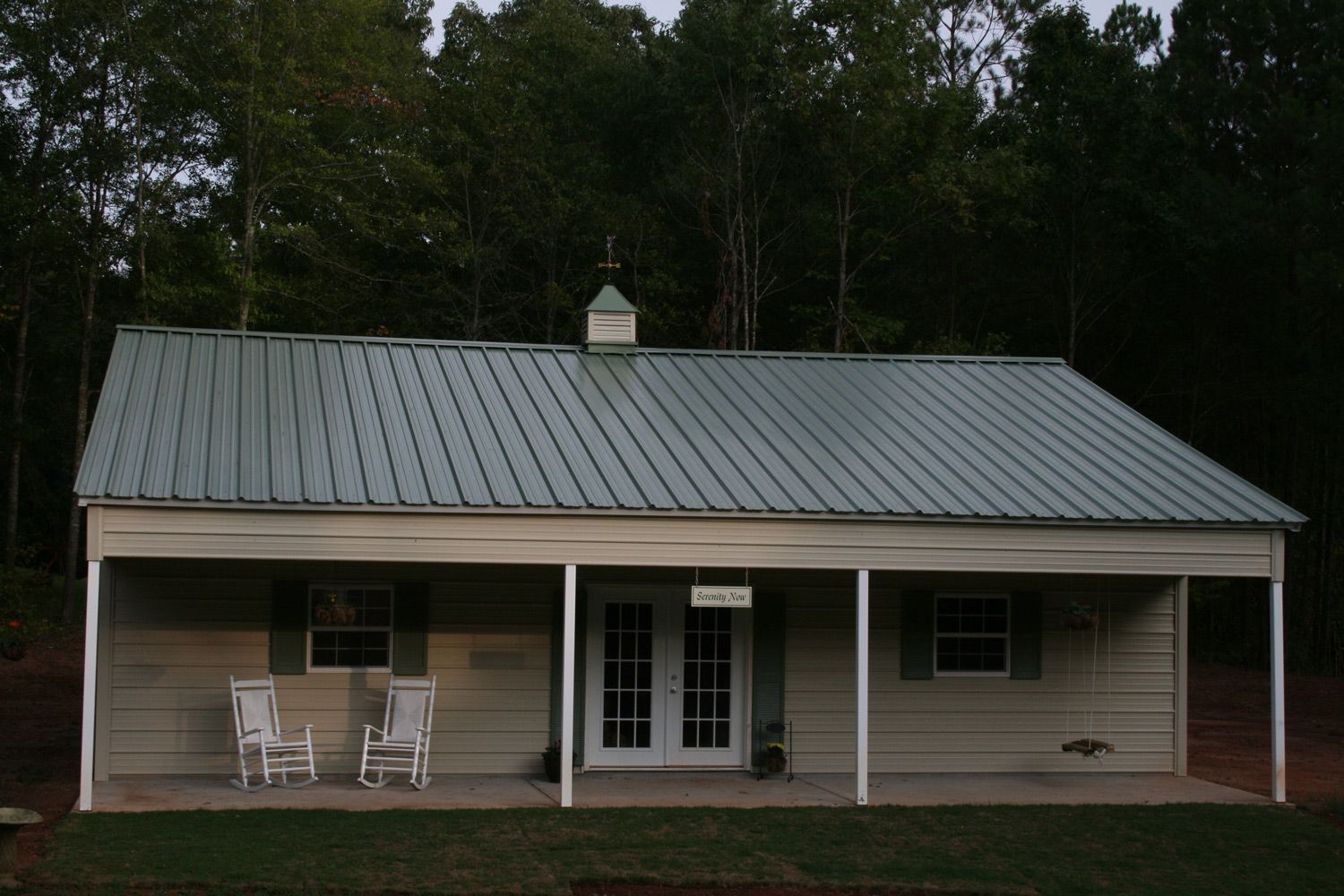 A white house with a metal roof and a porch
